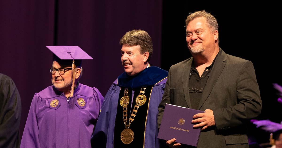 President Ken Kitts poses for a photo with Jay Johnson, son of the late Jimmy Johnson, and David Hood at the Fall 2021 commencement ceremony.